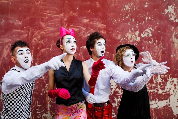 mimes debout sur un mur rouge