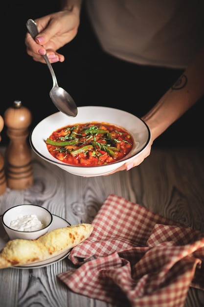 Minestrone appétissant avec des pousses d'asperges sur un petit pain frais sur un fond en bois clair