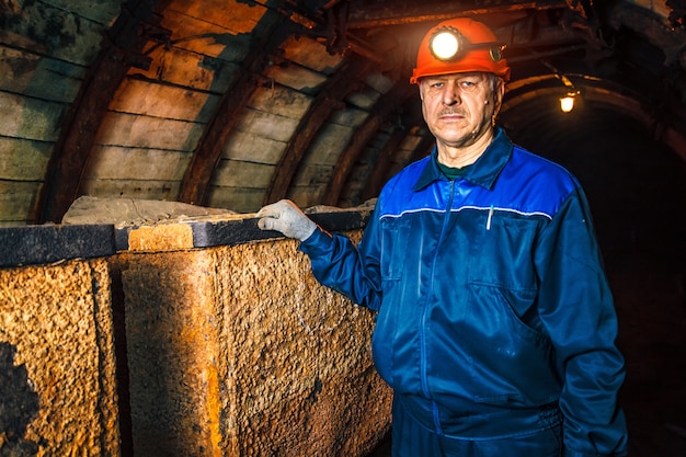 Un mineur dans une mine de charbon se trouve près d&#39;un chariot. Espace de copie.