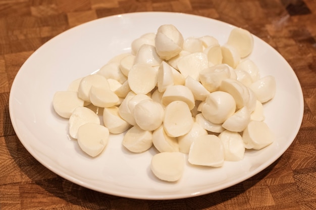 Mini boules de fromage mozzarella dans une assiette blanche sur une planche à découper en bois. ingrédient de la salade