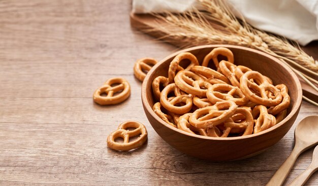 mini bretzel salé dans un bol en bois avec une cuillère et une fourchette sur fond de table en bois. copie espace