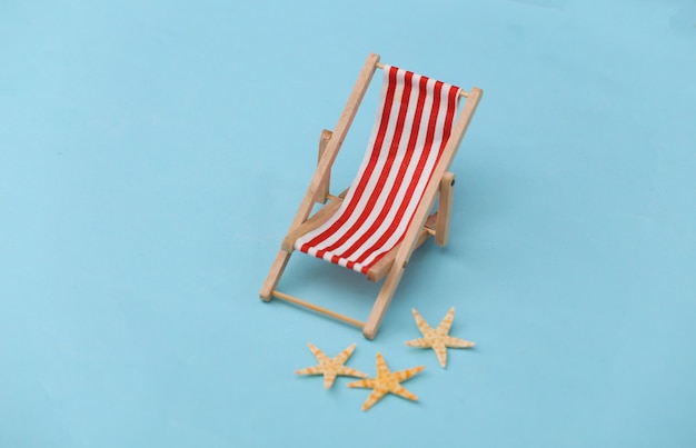 Mini chaise longue de plage et étoile de mer sur bleu. Symbole des vacances à la plage, station balnéaire