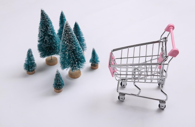 Mini chariot de supermarché et arbres de Noël sur fond blanc