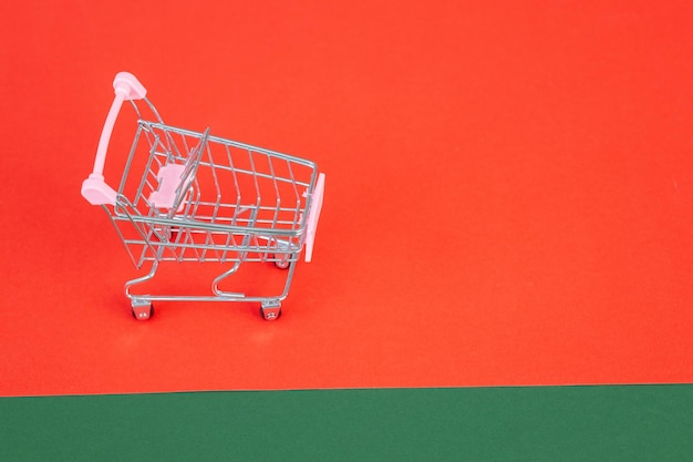 Mini chariot de supermarché sur fond vert rouge