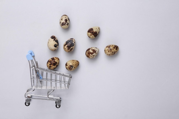 Mini chariot de supermarché avec œufs de caille sur fond gris Vue de dessus