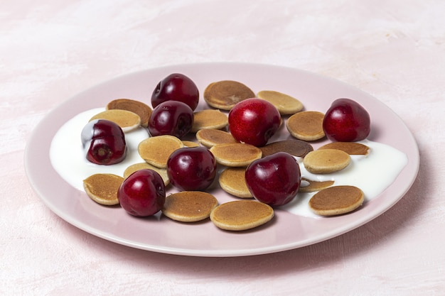 Mini crêpe de céréales maison avec du yaourt, du miel et des fraises sur une table colorée.