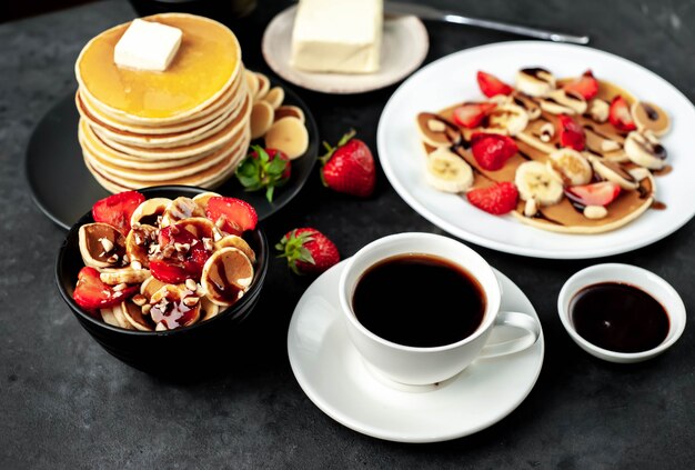 Mini crêpes aux fraises et bananes sur des assiettes sur la table