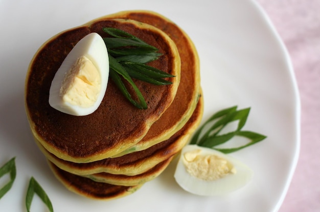 Mini crêpes aux œufs de caille et oignons verts sur une plaque blanche