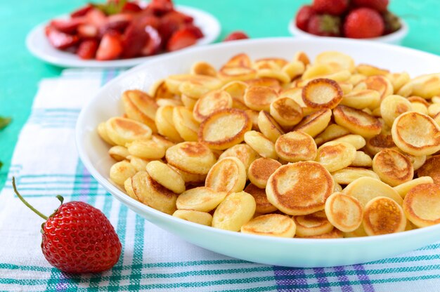 Mini crêpes dans un bol avec des fraises fraîches