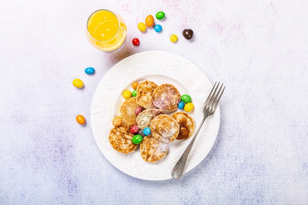 Mini crêpes hollandaises appelées poffertjes avec du sucre en poudre coloré et des bonbons. Concept d'aliments sains, mise à plat, vue de dessus, espace copie