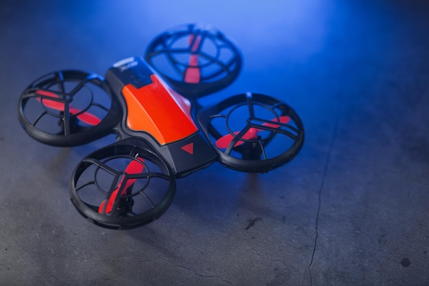 Un mini drone espion quadricoptère orange sur un sombre