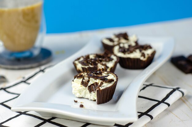 Mini gâteaux au fromage maison dans des paniers de chocolat et café au lait