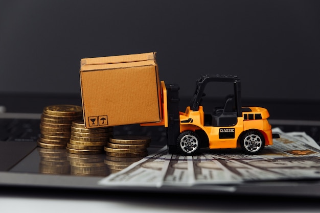 Mini modèle de chariot élévateur avec des boîtes et de l'argent sur le clavier close-up