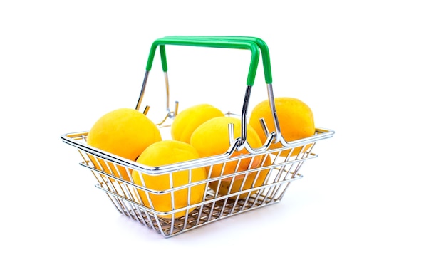 Mini panier de supermarché avec des abricots mûrs isolés sur fond blanc.