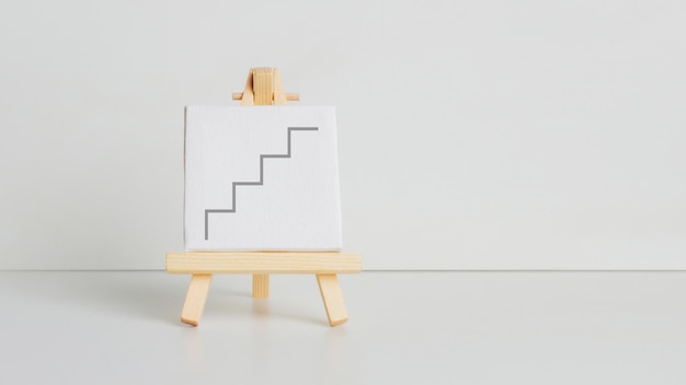 Mini peinture sur un chevalet sur fond clair Avec un escalier peint Symbole de réussite croissance augmentation promotion