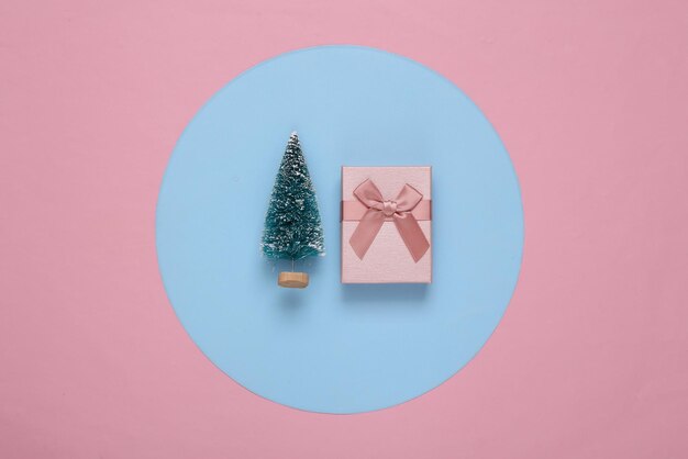 Mini sapin de Noël et coffret cadeau sur fond rond bleu rose Minimalisme