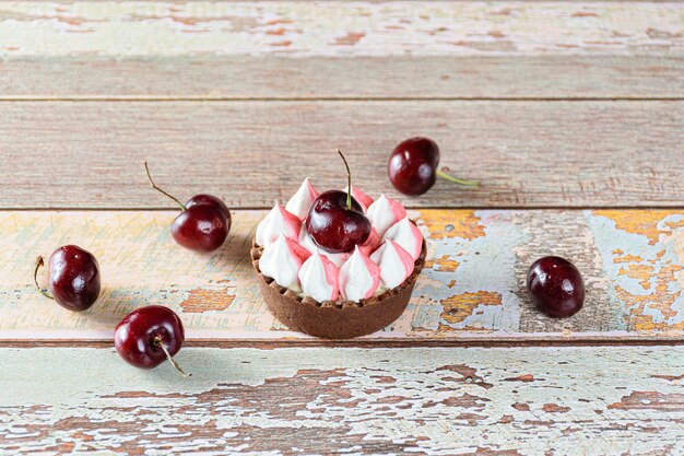 Mini tarte au chocolat avec ganache au chocolat, garnie de crème fouettée et de cerise. Entouré de cerises.