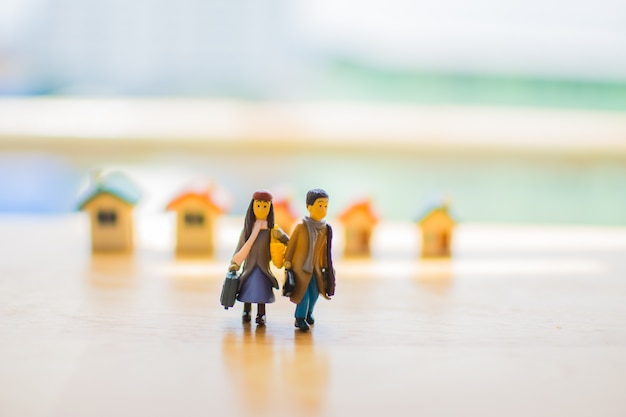 Miniature d&#39;amour de couple avec la maison sur la table en bois. le sujet est flou.