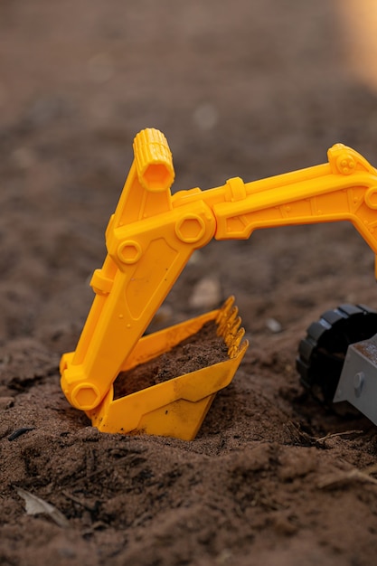 Miniature d'excavatrice de jouet de couleur jaune et noire au sol avec mise au point sélective