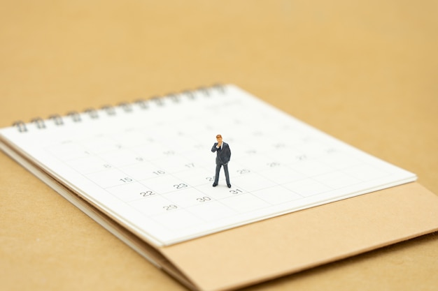 Miniature, hommes affaires, debout, sur, calendrier blanc