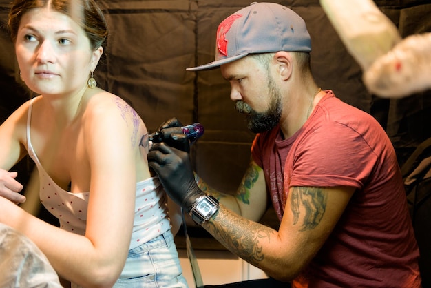 MINSK, BÉLARUS - 19 SEPTEMBRE 2015 Tatoueur professionnel faisant le tatouage sur le client.