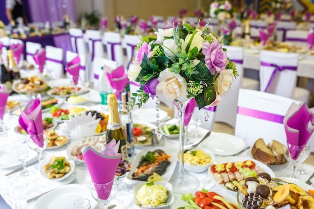 Minsk Biélorussie MAI 2014 Belles fleurs sur une table de dîner élégante au jour du mariage Décorations servies sur la table de fête en fond violet