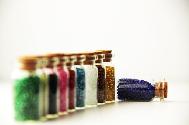 De minuscules bouteilles en verre remplies de différentes couleurs de perles