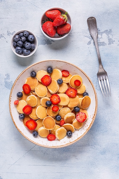 De minuscules crêpes aux fraises et myrtilles pour le petit déjeuner