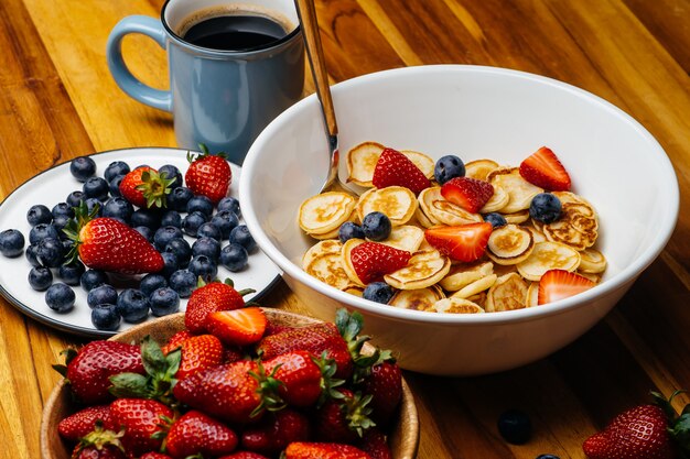 De minuscules crêpes pour le petit déjeuner. Crêpes aux fraises et bleuets cuits le matin pour le petit déjeuner dans la cuisine à domicile.