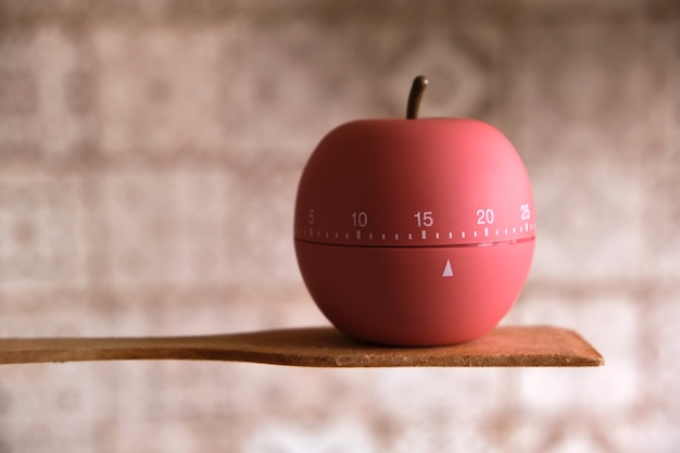 Minuterie de cuisine en forme de pomme se dresse sur une spatule en bois pour la cuisson ou la cuisson dans la cuisine