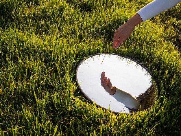 Photo miroir sur un champ herbeux avec le reflet d'une main coupée