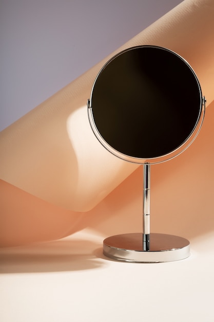 Miroir cosmétique argenté sur table. Espace de copie. Concentrez-vous sur les ombres