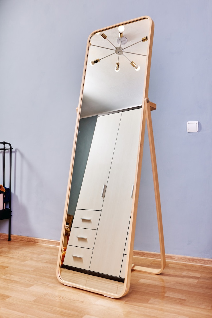 Photo le miroir de croissance se dresse dans la chambre sur un sol stratifié