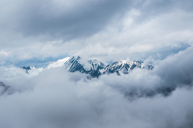 Mise au point douce. Magnifique paysage minimaliste avec de grands sommets enneigés au-dessus de nuages bas. Minimalisme atmosphérique avec de grands sommets enneigés, glacier sombre dans un ciel dramatique.