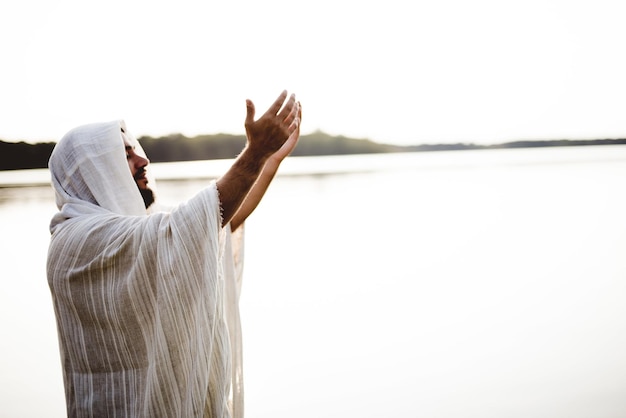 Mise au point peu profonde de Jésus-Christ priant les mains vers le ciel