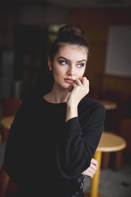 Mise au point peu profonde d'une jeune femme de race blanche brune avec un maquillage simple posant à l'intérieur