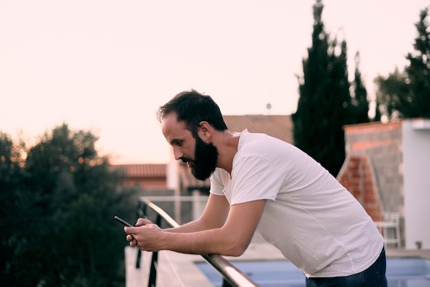 Mise au point peu profonde d'un jeune homme de race blanche à l'aide de son smartphone