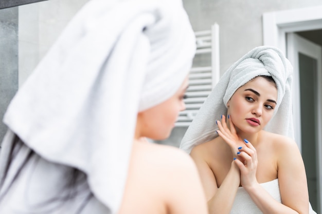 Mise Au Point Sélective De La Belle Jeune Femme Souriante Touchant Le Visage Tout En Regardant Le Miroir