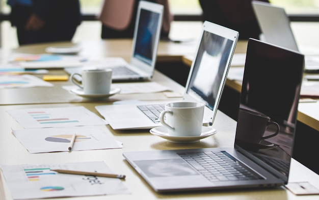 Mise au point sélective sur le bureau, groupe de femmes d'affaires méconnaissables se tenant ensemble au bureau à l'heure de la pause. Travail d'équipe d'employées prenant avec se détendre en arrière-plan flou.