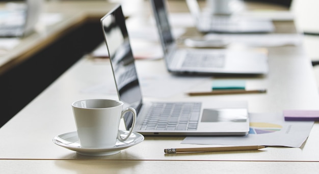 Mise au point sélective sur le bureau, groupe de femmes d'affaires méconnaissables se tenant ensemble au bureau à l'heure de la pause. Travail d'équipe d'employées prenant avec se détendre en arrière-plan flou.