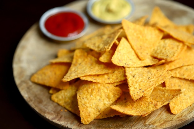 Mise au point sélective Chips de maïs nachos avec sauces sur une planche en bois Snack mexicain