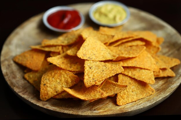 Mise au point sélective Chips de maïs nachos avec sauces sur une planche en bois Snack mexicain