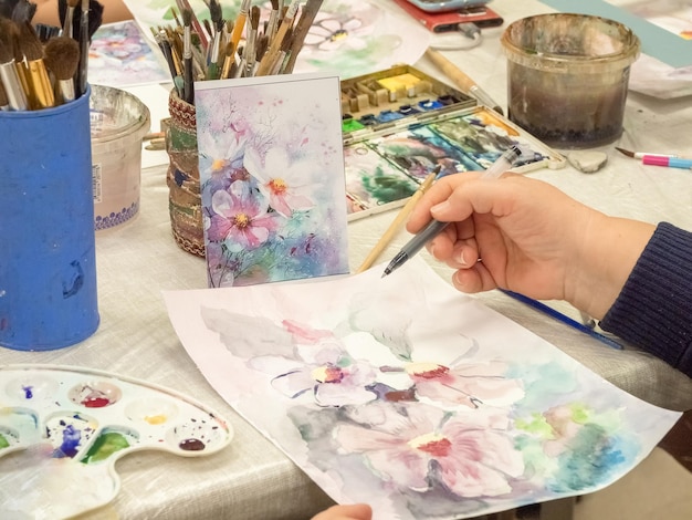 Mise au point sélective Croquis à l'aquarelle Vue à la première personne de l'enseignement du dessin Pinceau entre les mains de l'artiste peinture à l'aquarelle créativité avec de nombreuses couleurs