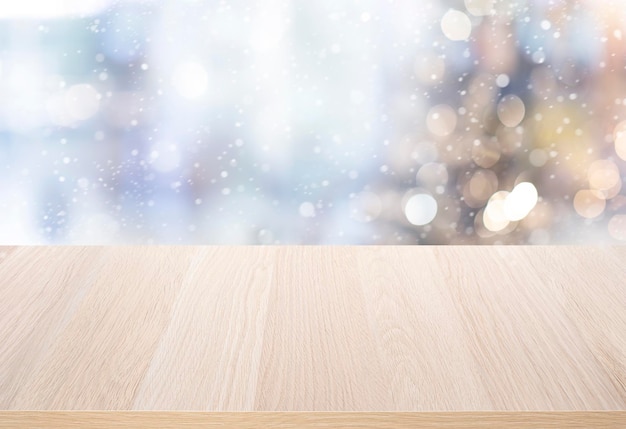 Photo mise au point sélective dessus de table en bois vide avec chutes de neige et flou d'arbre de noël sur fond d'hiver