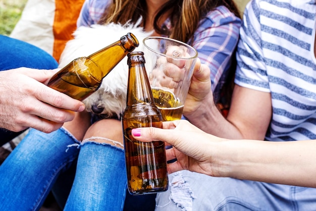 Mise au point sélective du groupe d'amis faisant tinter des bouteilles de bière