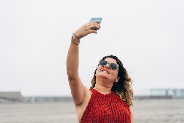 Mise au point sélective, une femme heureuse prend un autoportrait avec son smartphone