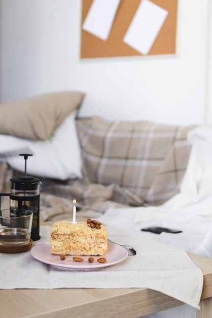 Mise au point sélective sur un gâteau avec une bougie allumée sur le fond d'un canapé contre un mur blanc