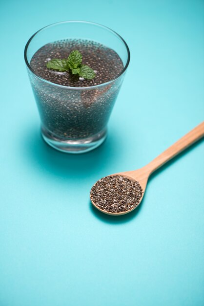 Photo mise au point sélective des graines de chia à boire avec de l'eau dans un verre transparent avec de la mélisse.