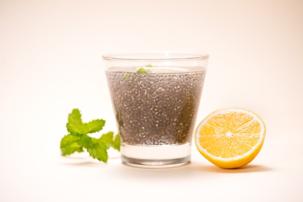 Mise au point sélective des graines de chia à boire avec de l'eau dans un verre transparent avec de la mélisse.