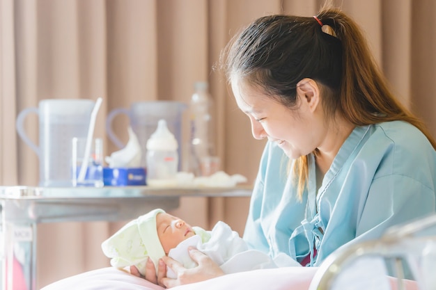 Mise au point sélective de Heureuse mère asiatique à la recherche d&#39;un garçon nouveau-né dort dans la main à l&#39;hôpital